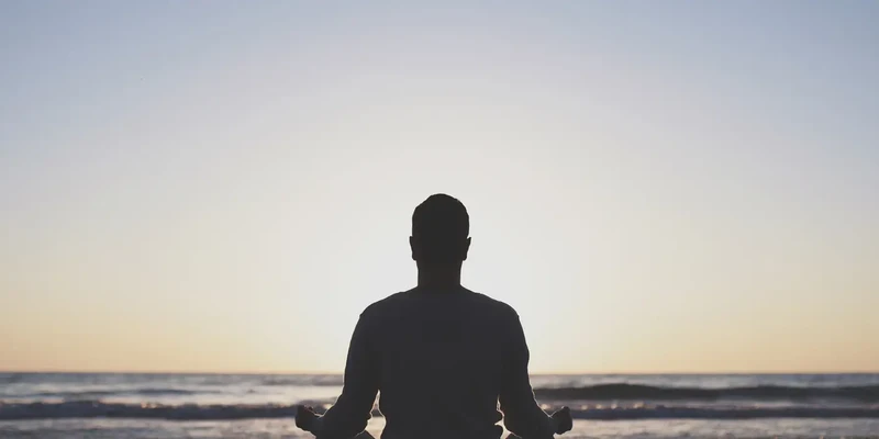 man meditating at the beach